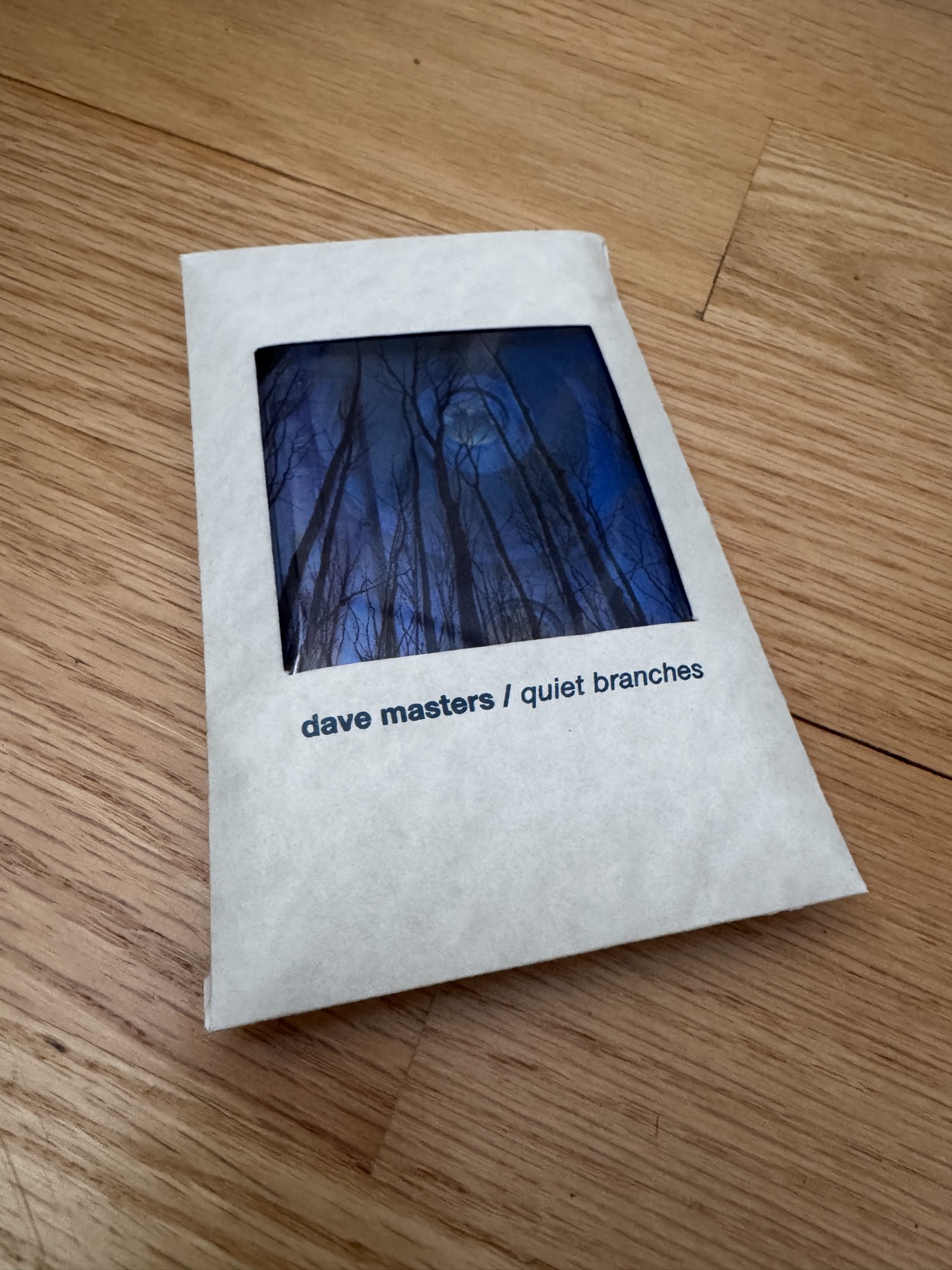 quiet branches cassette in a hand-folded glassine sleeve with a die-cut window showing the cover art